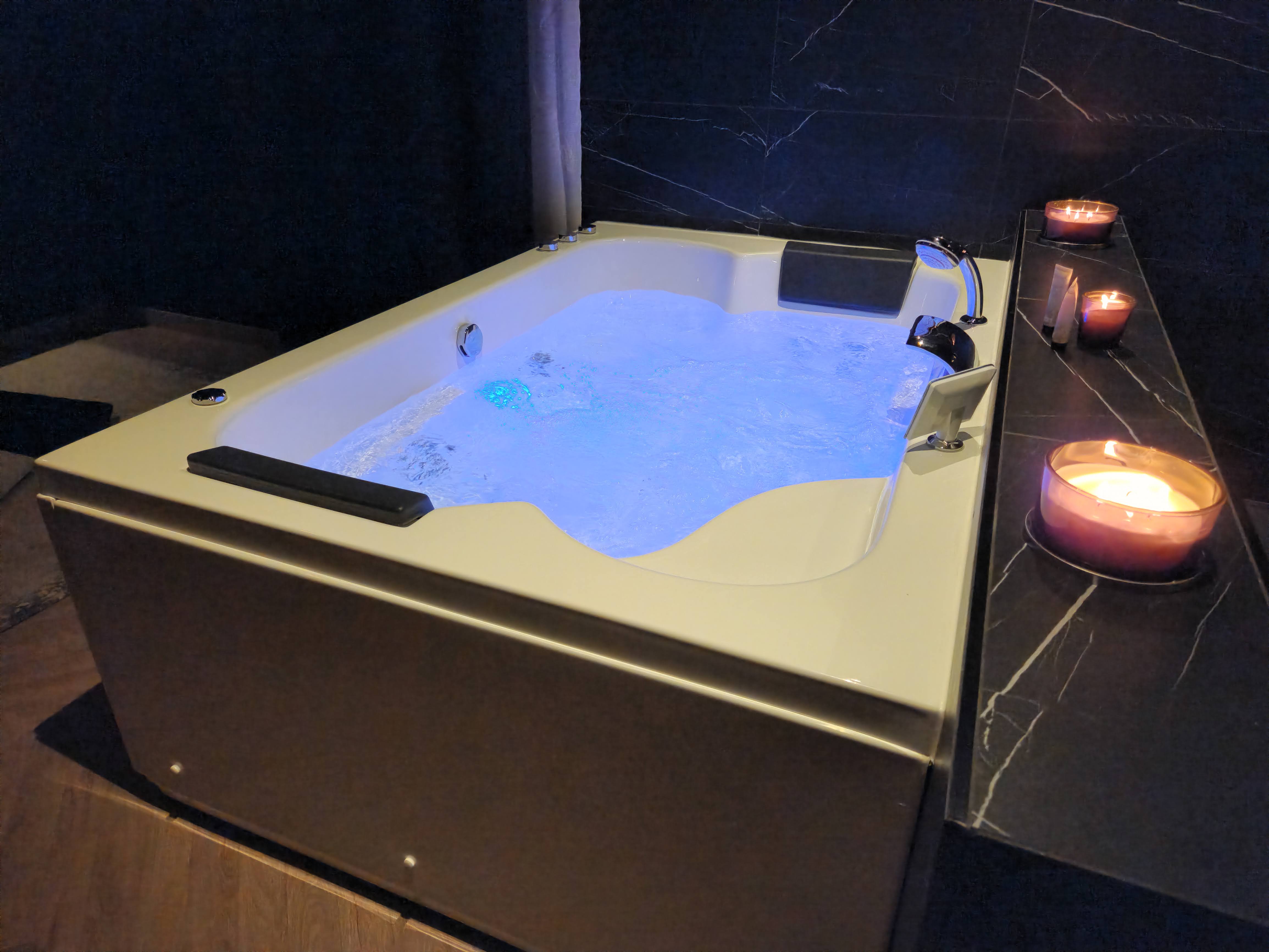 Love Room L'Aixtase - Atmosphère intime avec bougies parfumées disposées autour du spa